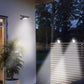 Two glowing solar clip-on garden lights on fence at night near house wall