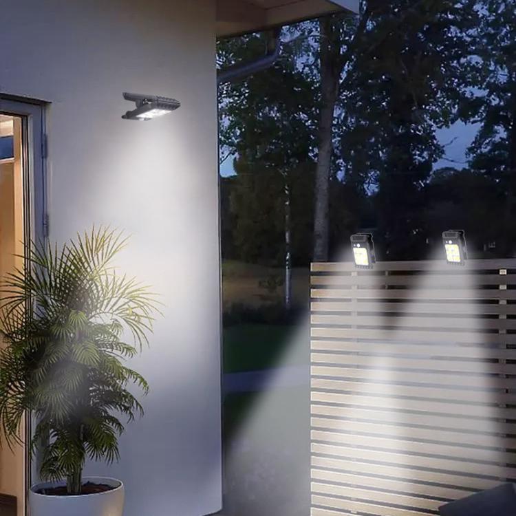 Two glowing solar clip-on garden lights on fence at night near house wall