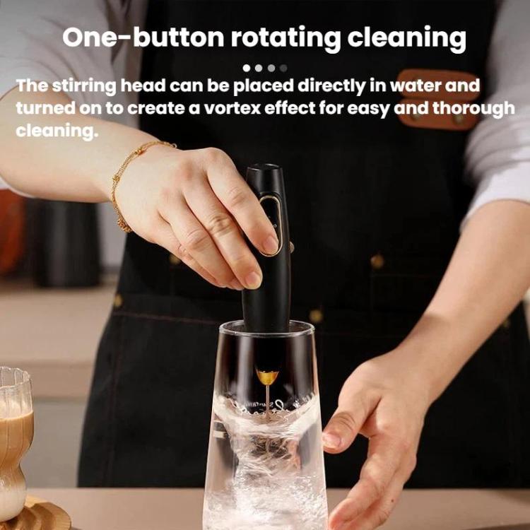 Black handheld milk frother in a clear cup, showing rotating whisk cleaning motion.