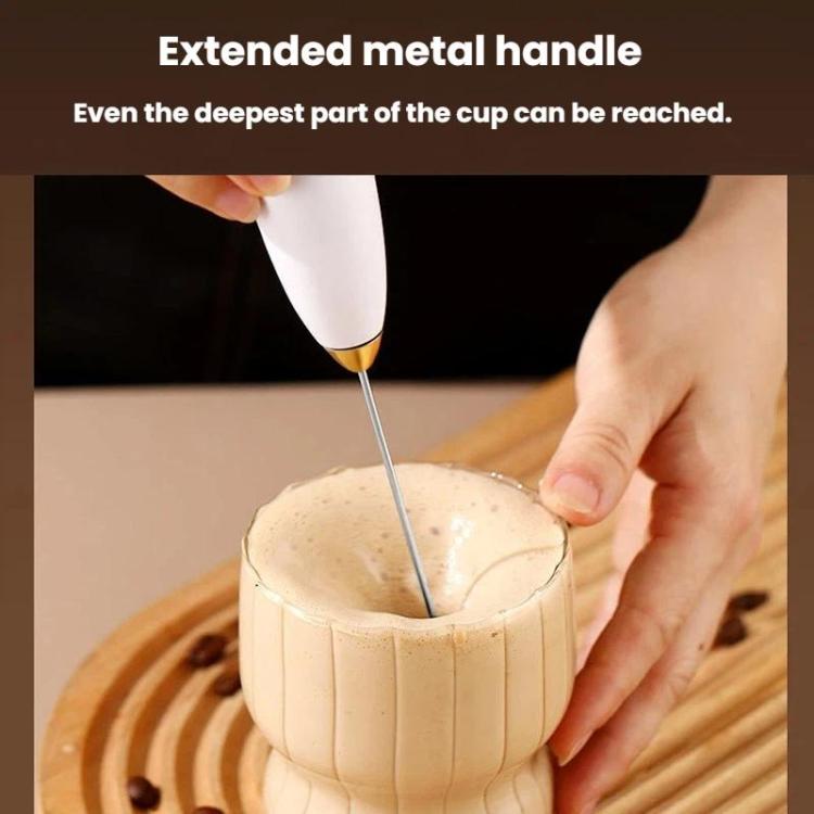 Handheld milk frother dipping into a cup to mix milk foam.
