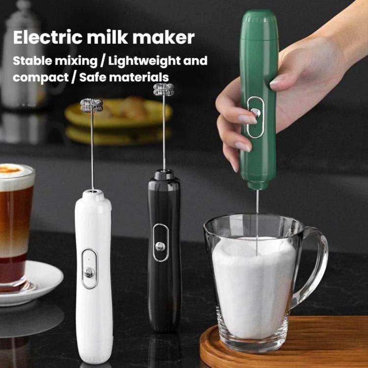 Handheld milk frother whisk in green, held over glass mug of foamy milk