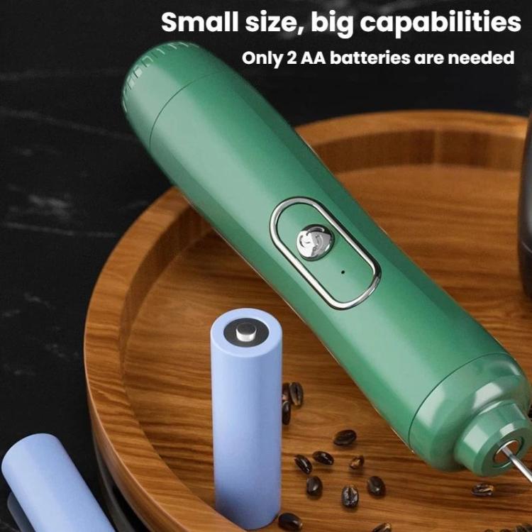 Compact handheld milk frother, green body beside AA batteries and scattered beans