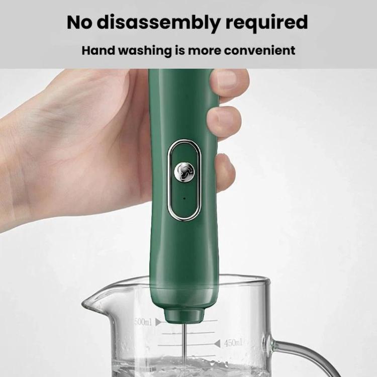 Green handheld milk frother whisk in hand, inserted into a measuring beaker