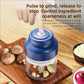 Blue electric mini chopper on wood board with clear cup and stainless blade insert