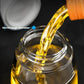 Electric oil sprayer bottle close-up, yellow oil stream into clear container