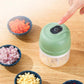 Green rechargeable mini food chopper held above the countertop with food bowls nearby