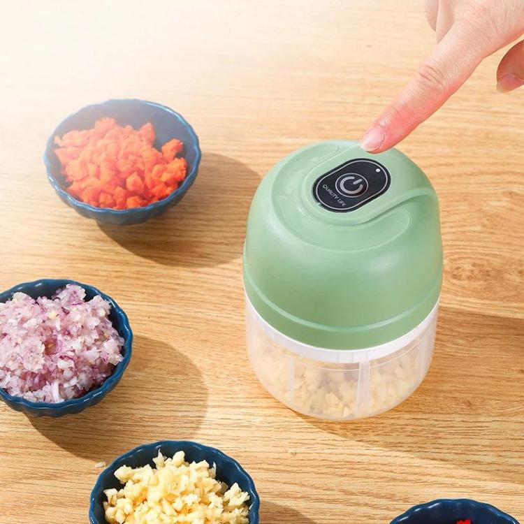 Green rechargeable mini food chopper held above the countertop with food bowls nearby