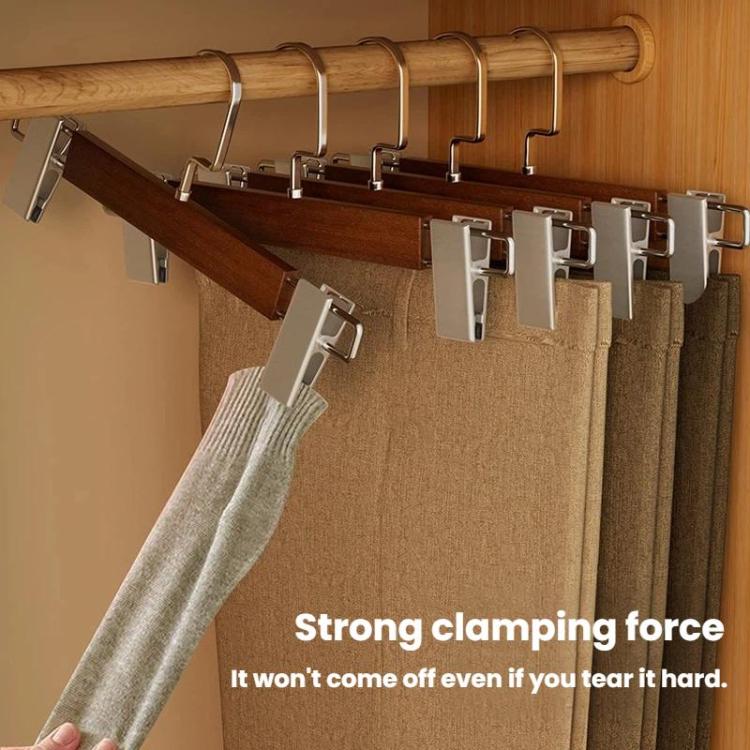 Clothes hanger with brown wooden bar and black clamps holding folded pants fabric