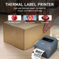 Gray thermal label printer with shipping label coming out beside a box