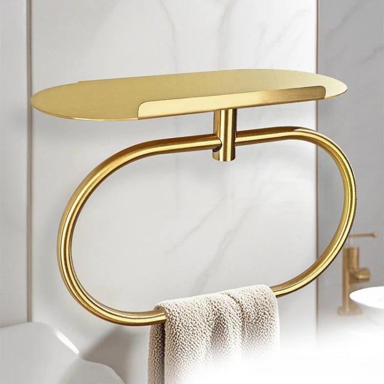 Gold stainless steel towel ring with oval shelf holding a folded towel.