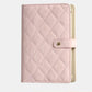 Pink quilted jewelry organizer book with snap front strap and cream interior backing.