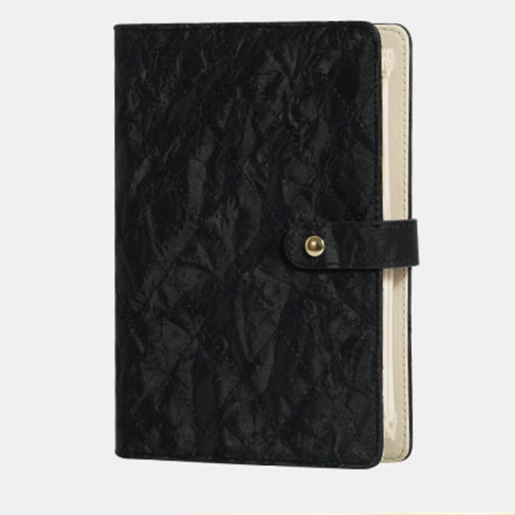 Black quilted jewelry organizer book with snap front strap and beige interior backing.