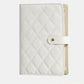 White quilted jewelry organizer book with snap front strap and cream interior backing.