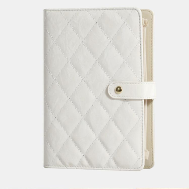 White quilted jewelry organizer book with snap front strap and cream interior backing.