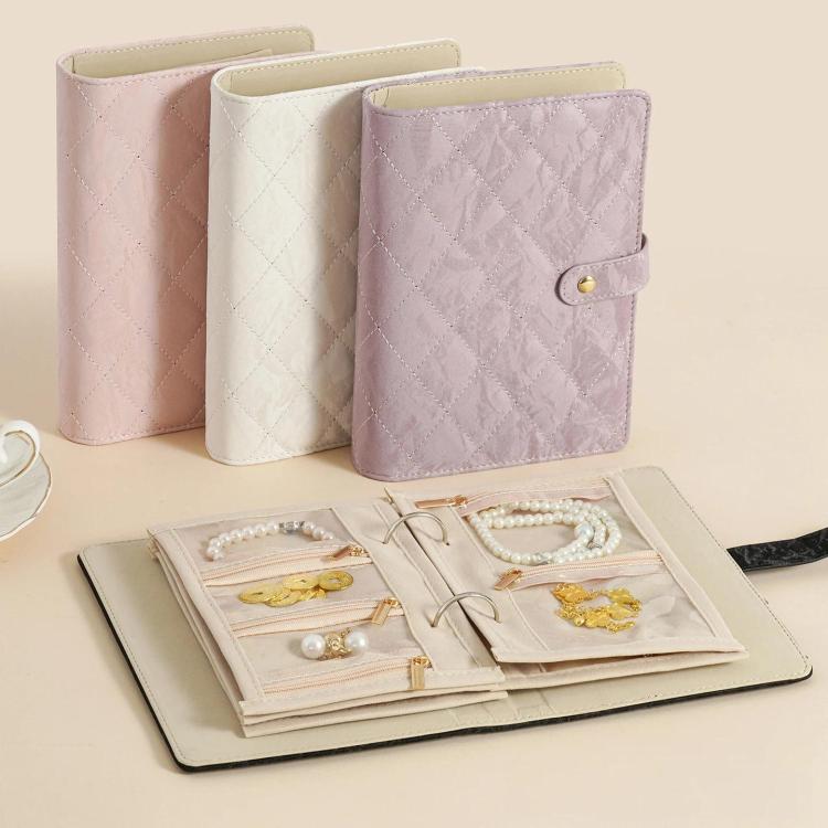 Set of quilted jewelry organizer books in lavender, white, and light pink with snap closures.