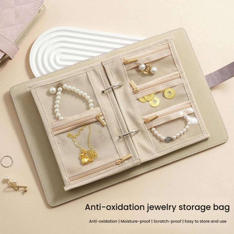 Beige jewelry organizer book open with clear compartments and slots for necklaces and rings.
