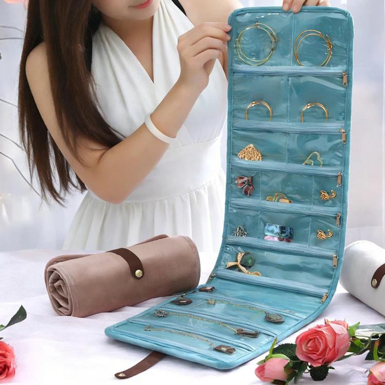 Person holding a light blue roll-up jewelry organizer bag with multiple transparent pockets