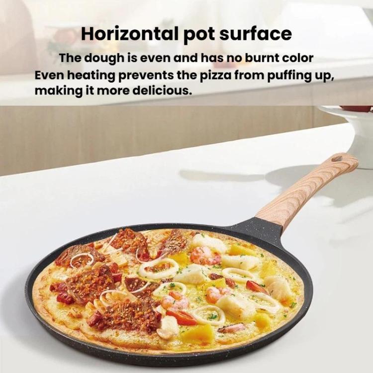 Black non-stick pizza pan with wooden handle holding a topped pizza.