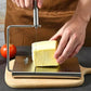 Stainless steel cheese slicer cutting a cheese block with guide wire