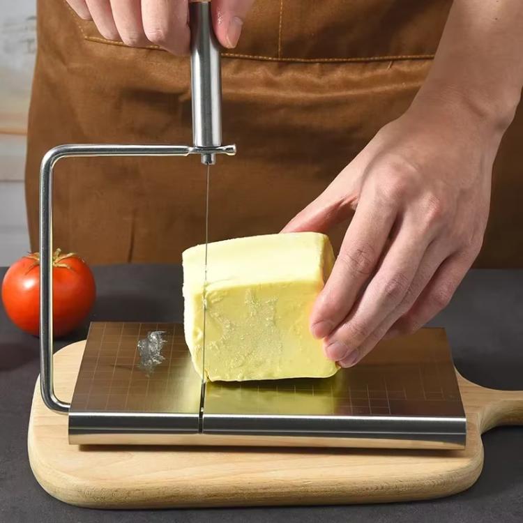 Cheese slicer in use: hands guide wire to slice cheese on stainless base