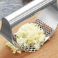 Stainless steel garlic press crushing garlic into fine pieces on perforated tray