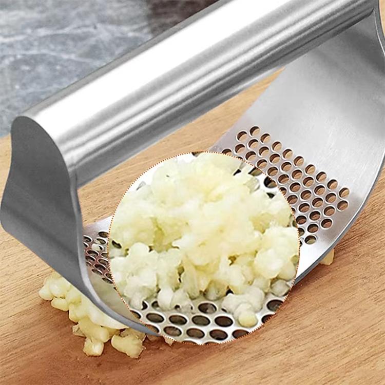 Stainless steel garlic press crushing garlic into fine pieces on perforated tray