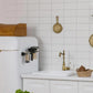 Black wall-mounted acrylic holder with cup slots on a kitchen backsplash