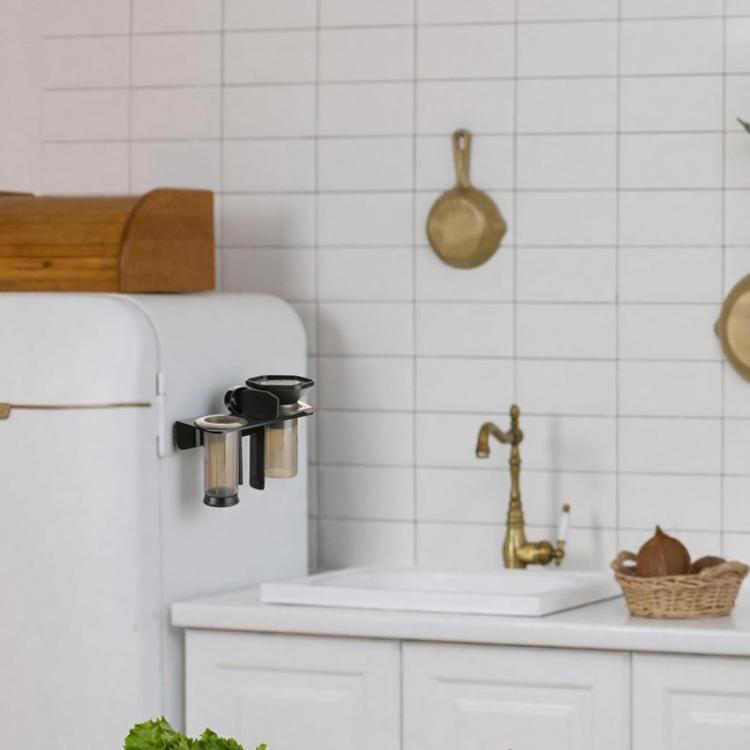 Black wall-mounted acrylic holder with cup slots on a kitchen backsplash