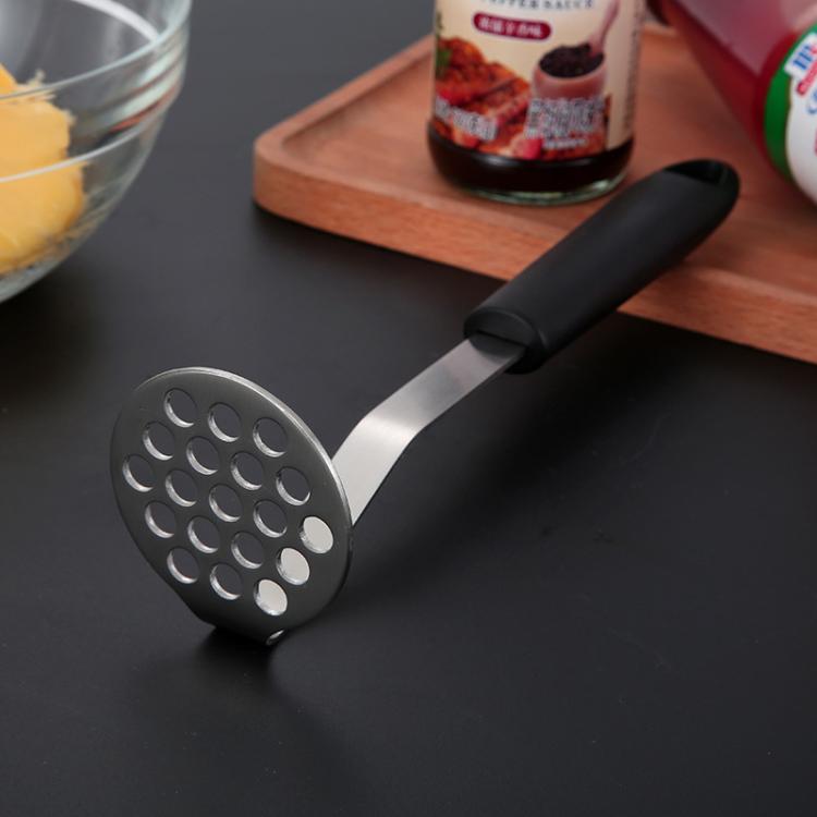 Potato masher with perforated stainless mashing head and black silicone grip handle.