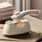 White handheld steam iron with gold trim steaming fabric