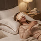 Light satin sleep mask with ruffled edge and elastic strap worn on the face