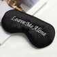 Black satin sleep mask with “Leave Me Alone” lettering and black edging