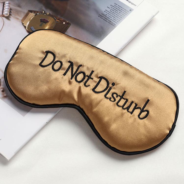 Champagne gold satin sleep mask with “Do Not Disturb” lettering and black trim