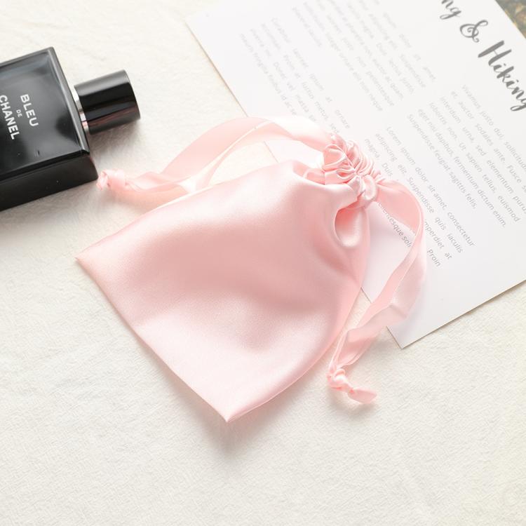Light pink satin drawstring pouch for small jewelry, gathered top with ribbon ties.