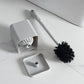 Toilet brush and holder set with white handle, black bristle head, and gray base