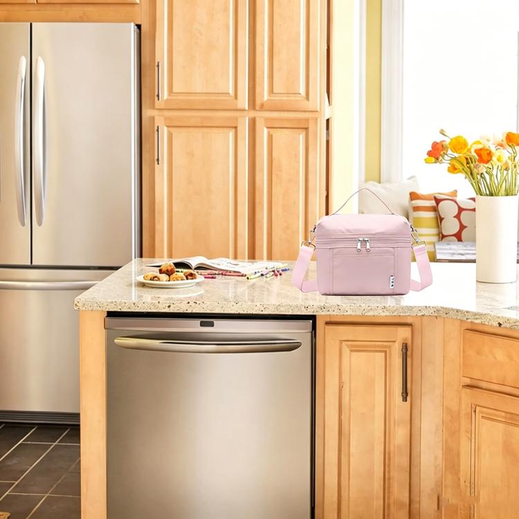 Pink insulated lunch bag with top handle and shoulder strap on a countertop