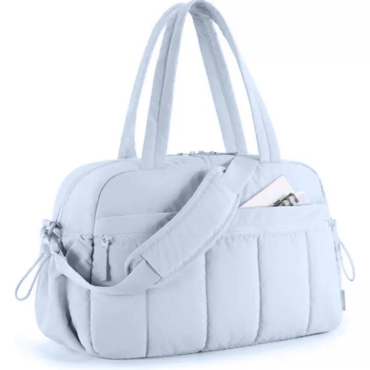 Light blue travel bag with compartments, padded strap, and zippered front pocket