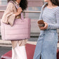 Large pink tote bag with wide base and multiple compartments, carried for travel