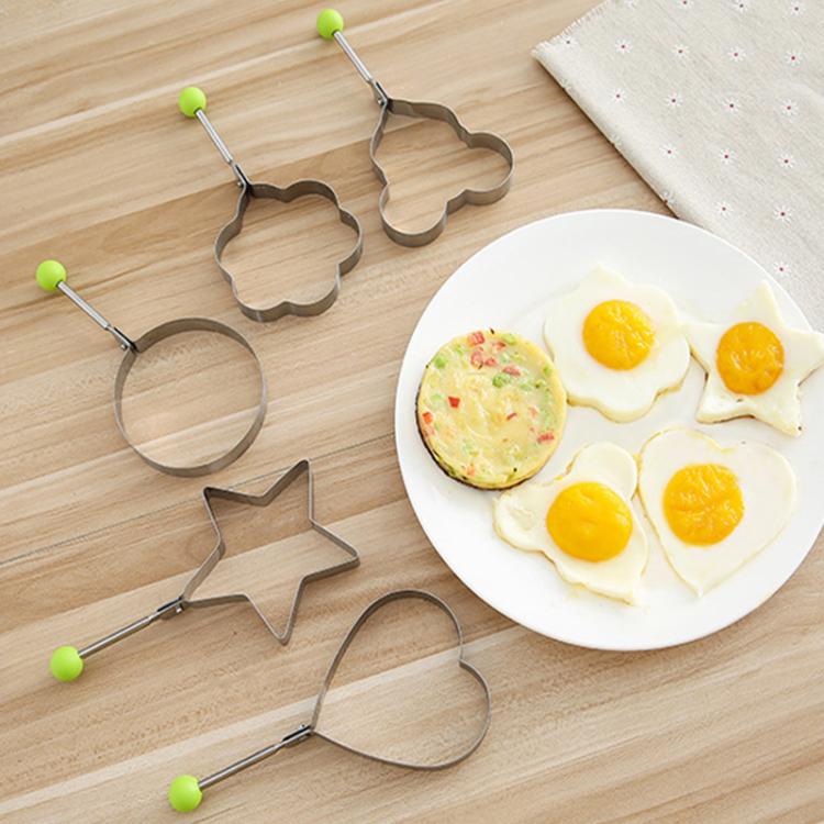 Five egg molds with handles and green knobs for shaping sunny-side eggs