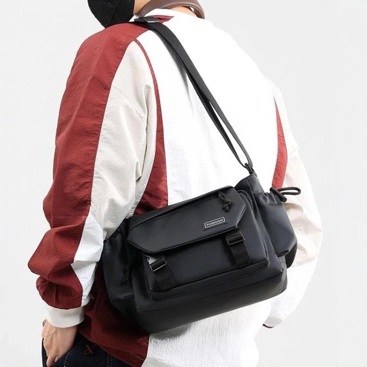 Black crossbody messenger bag worn on shoulder with flap front and buckled strap