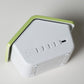 White house-shaped digital alarm clock side view with green roof and control buttons