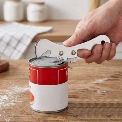 Stainless steel can opener with lever, held by hand opening a can