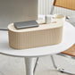Desktop cable management box with wood or light ribbed body, showing cord space on table.