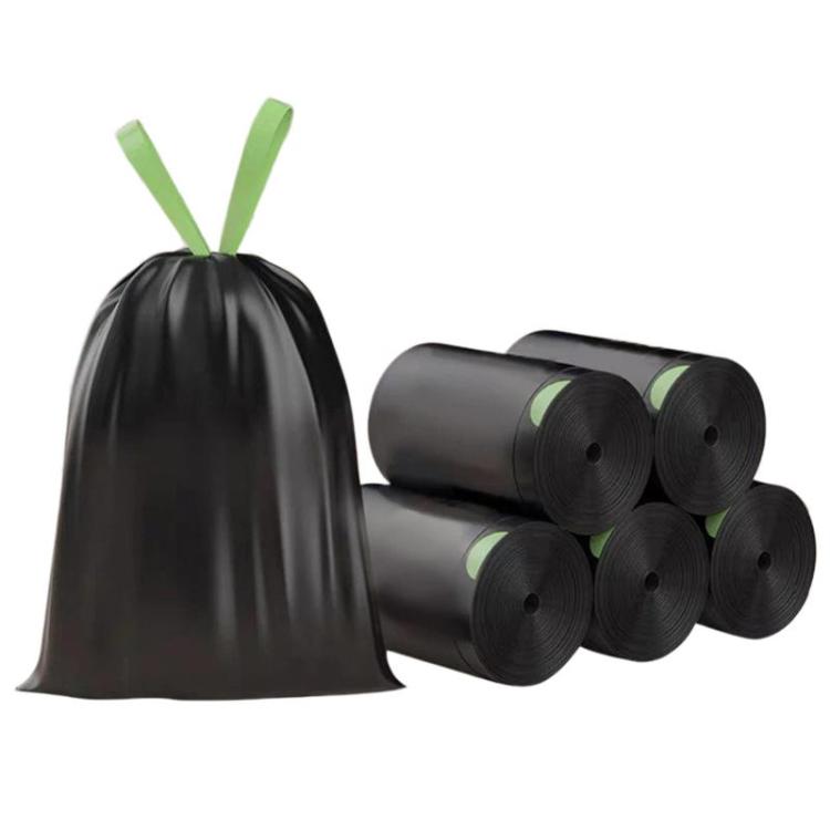 Black drawstring trash bags with green leaf accents; rolls stacked together
