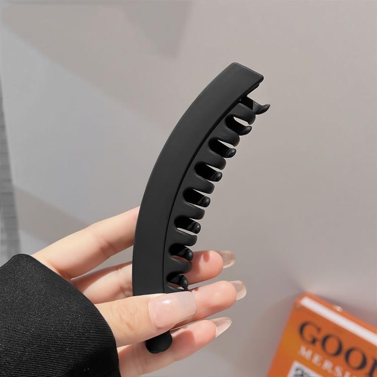 Black banana hair clip with curved grip and pointed prongs for styling hair