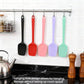Hanging silicone spatulas in black, red, pink, purple, and mint with loop handles