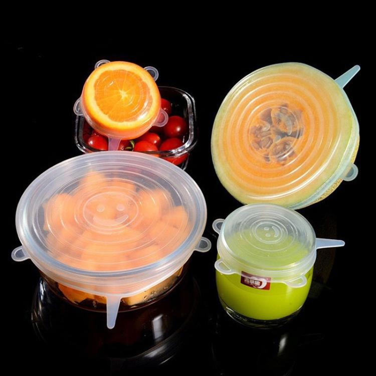 Clear silicone food storage lids covering bowls of fruit, round with tab handles