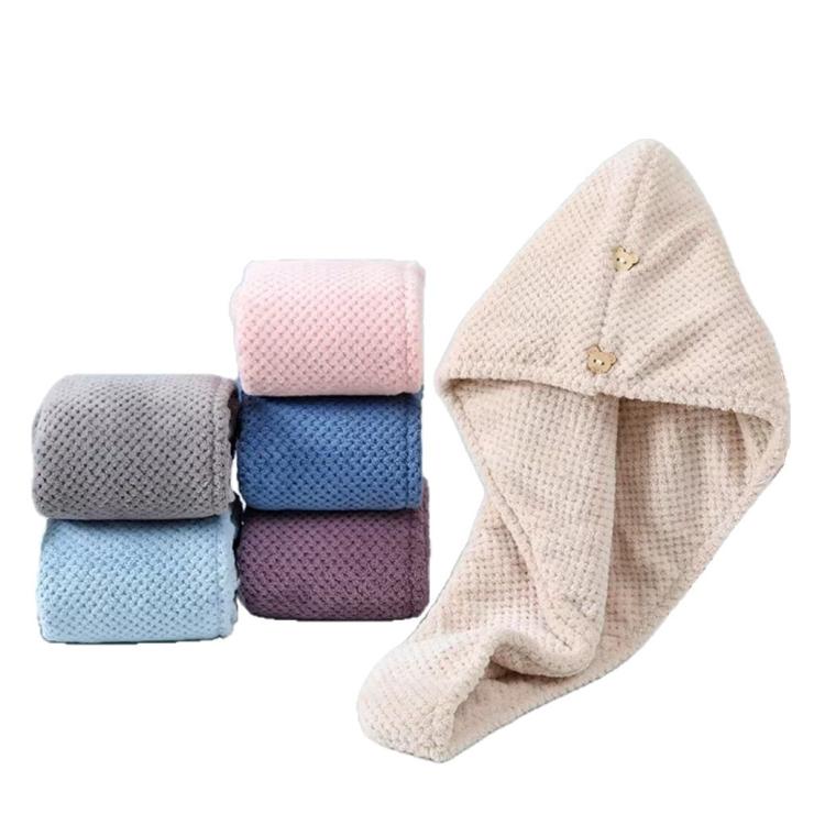 Cream hair drying cap beside stacked folded coral fleece towels in pastel colors