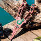 Pink hook remover pliers with line cutter, shown gripping a branch.