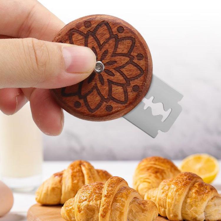 Handheld wooden bread slicer with flower-carved disc and blade extended for slicing